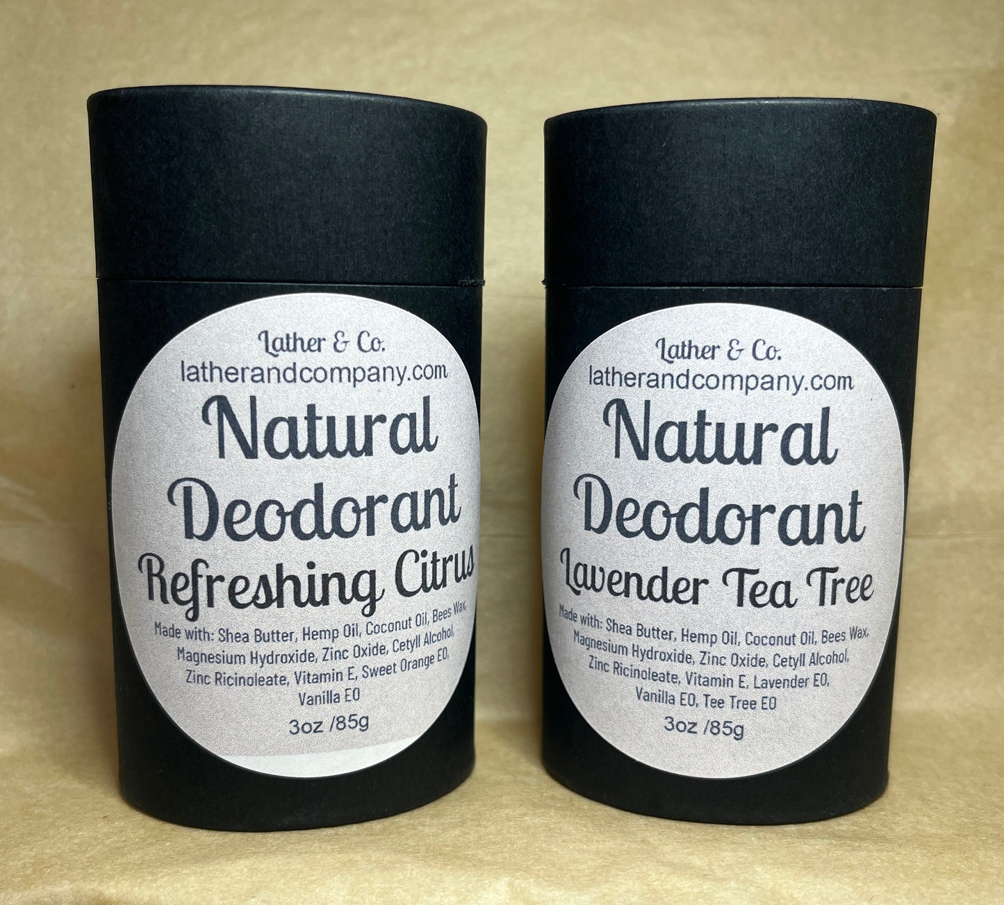 Two cylindrical eco-friendly paperboard deodorant tubes with black lids. The labels indicate the scent is either Lavender Tea Tree or Refreshing Citrus, and the brand is Lather & Co.