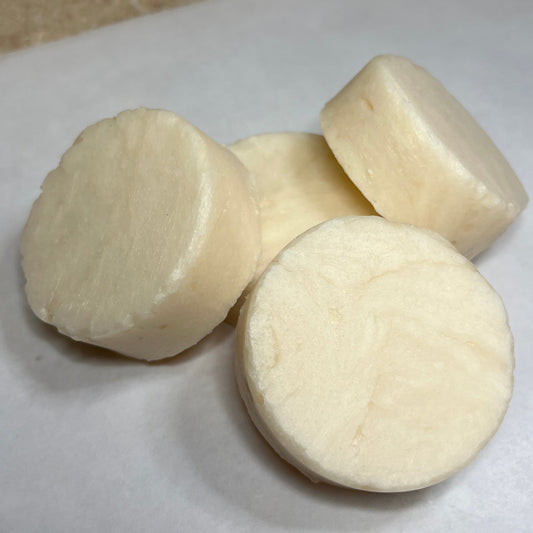 A photo showing a collection of white, round shampoo bars on a white surface.
