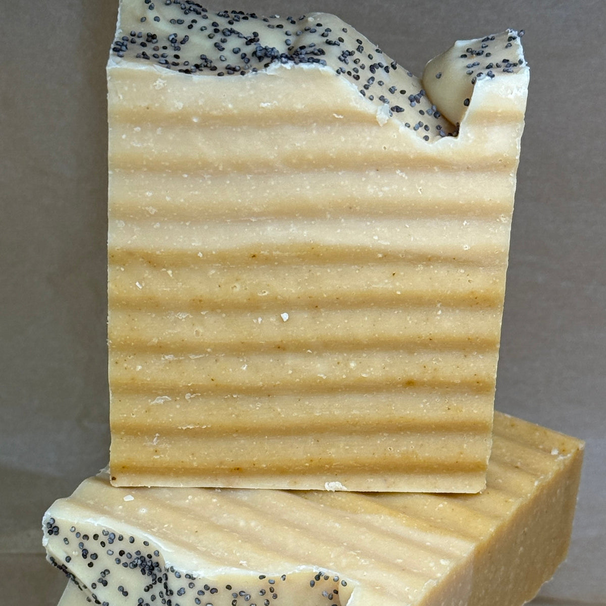 Stack of handmade soap bars with specks on a gray background