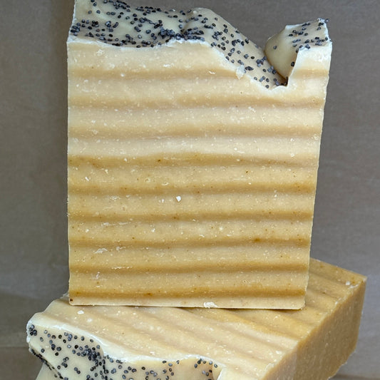 Stack of handmade soap bars with specks on a gray background