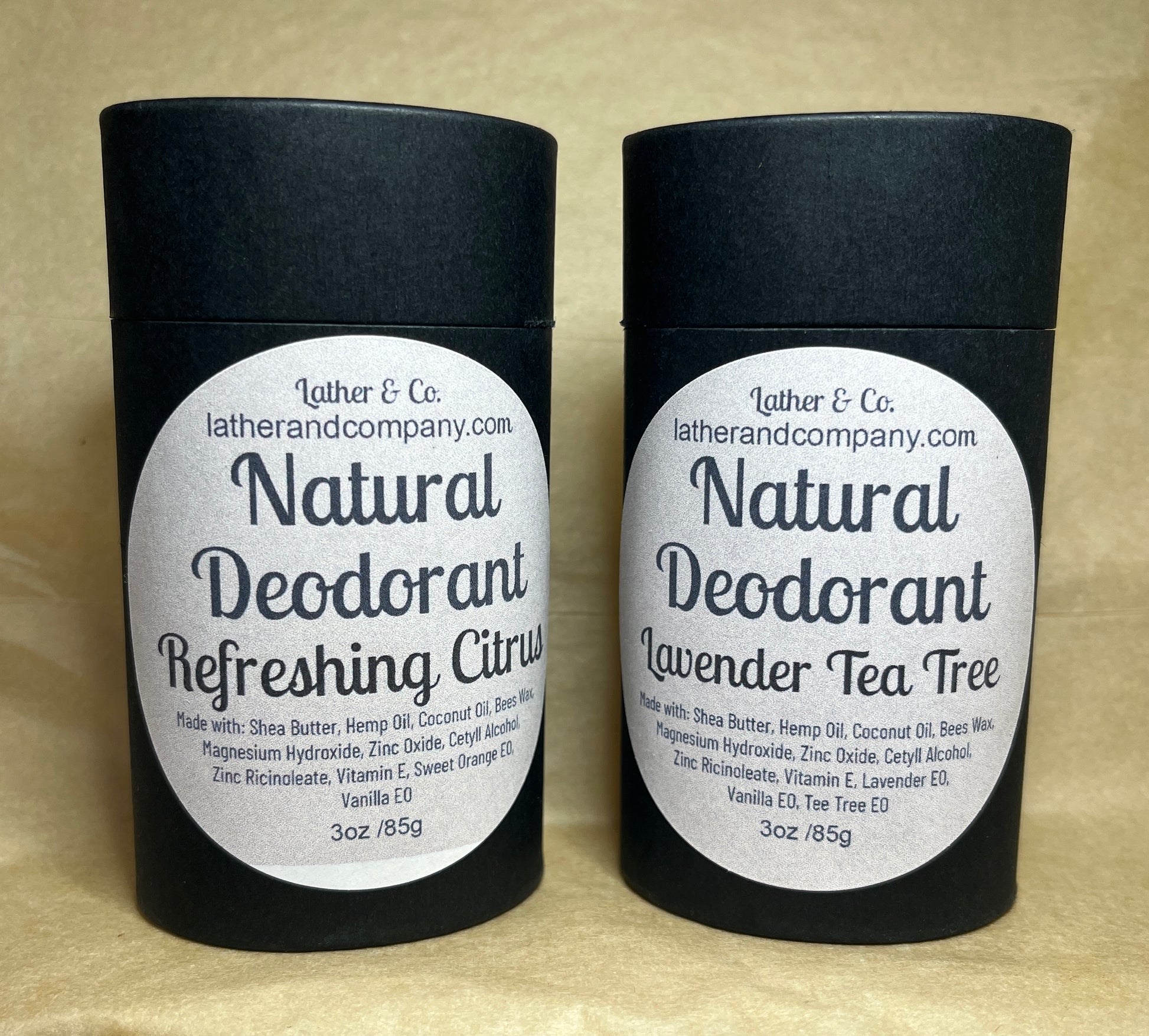 Two cylindrical eco-friendly paperboard deodorant tubes with black lids. The labels indicate the scent is either Lavender Tea Tree or Refreshing Citrus, and the brand is Lather & Co.