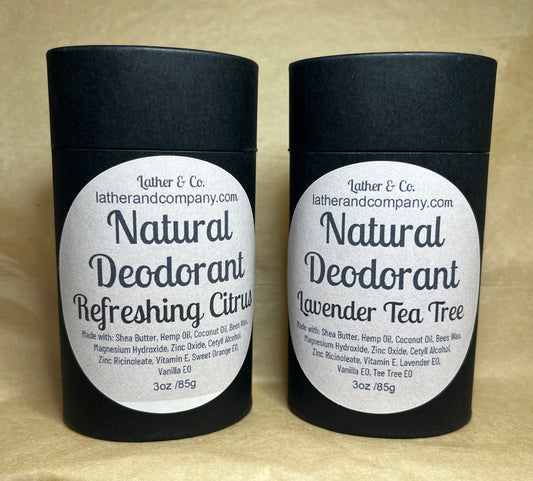 Two cylindrical eco-friendly paperboard deodorant tubes with black lids. The labels indicate the scent is either Lavender Tea Tree or Refreshing Citrus, and the brand is Lather & Co.