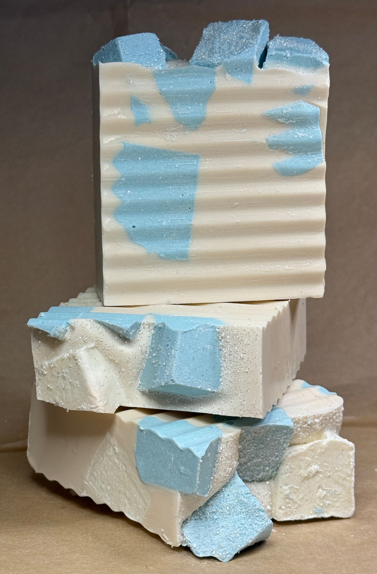 Stack of textured soap bars with blue and beige patterns on a brown background