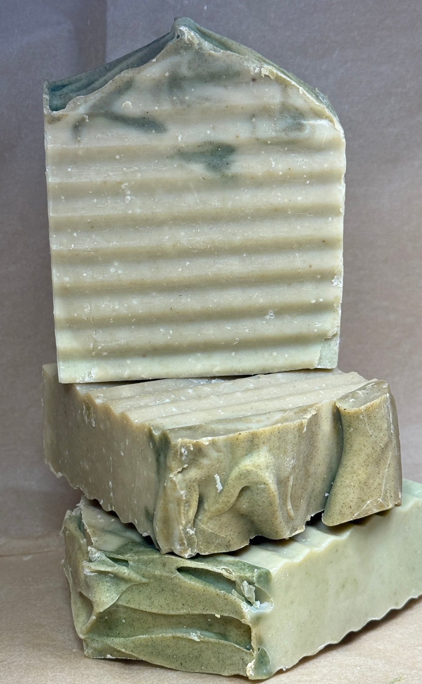 Three bars of green soap stacked on a gray background