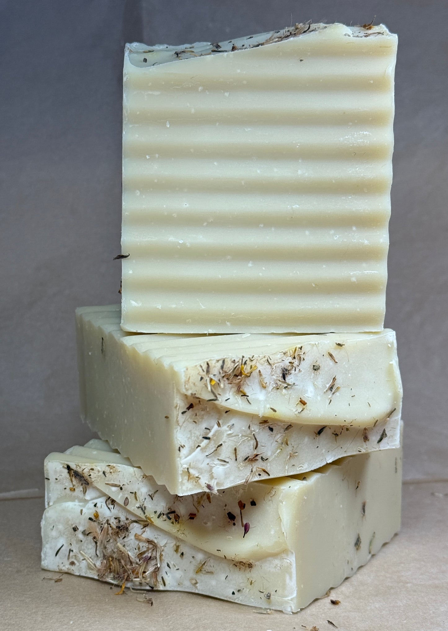 Stack of handmade soap bars with natural textures on a neutral background