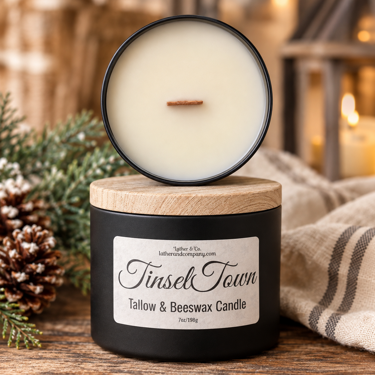 A black candle jar with a light wood lid, shown with the lid propped open above the jar. The candle wax is creamy off-white and has a single wick.