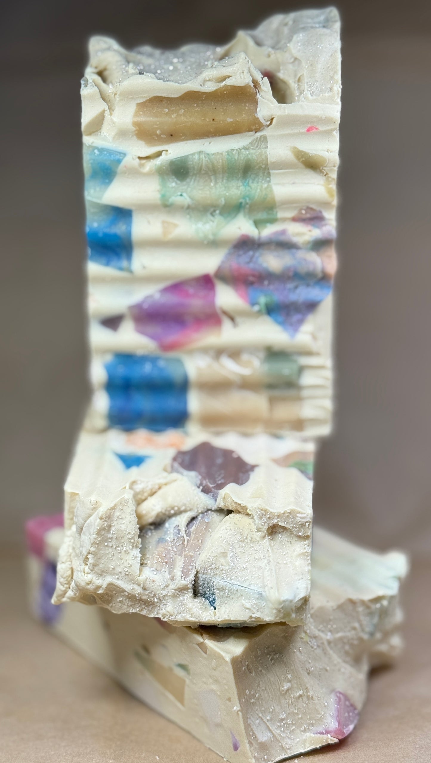 Stack of colorful soap bars with a textured surface on a neutral background