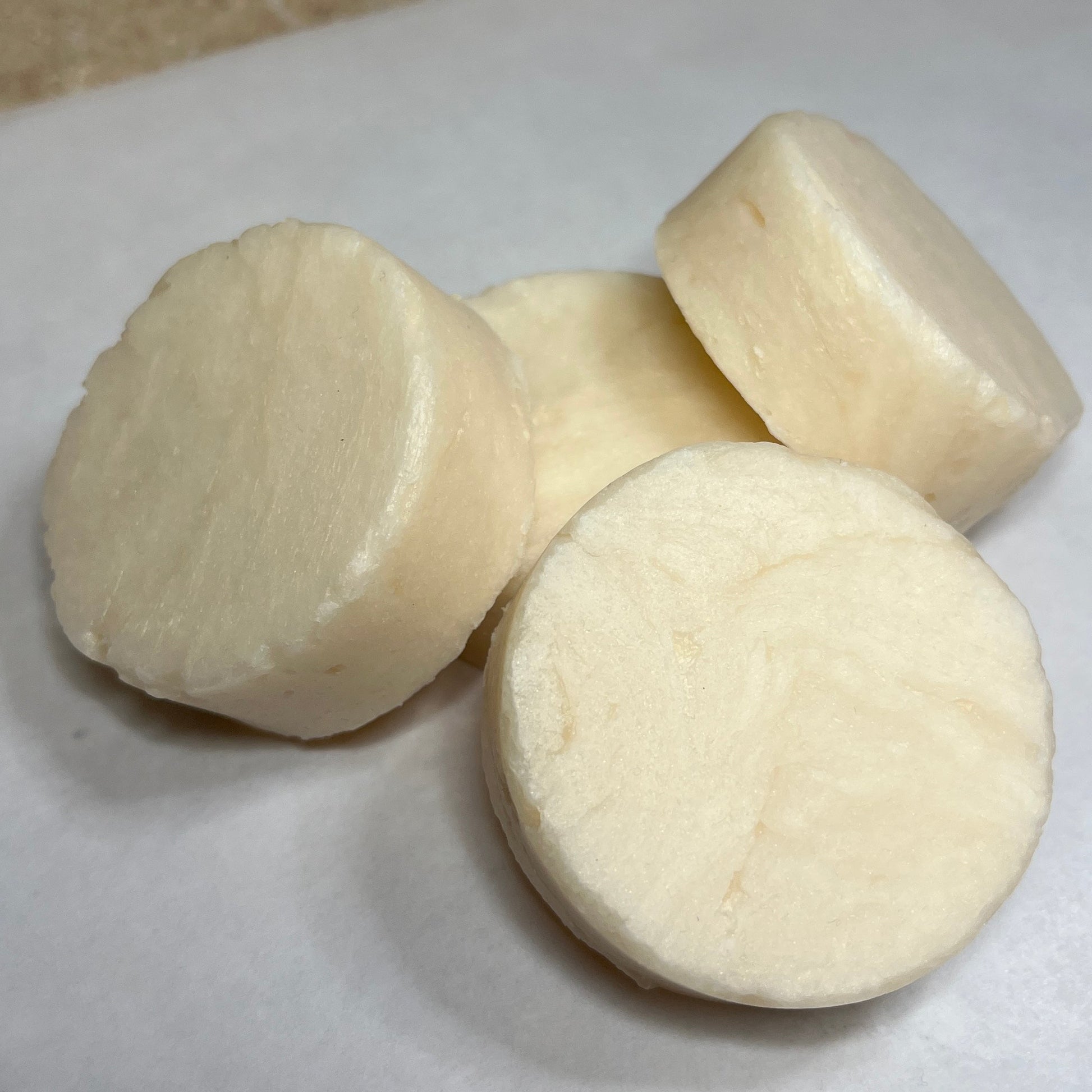 A photo showing a collection of white, round shampoo bars on a white surface.