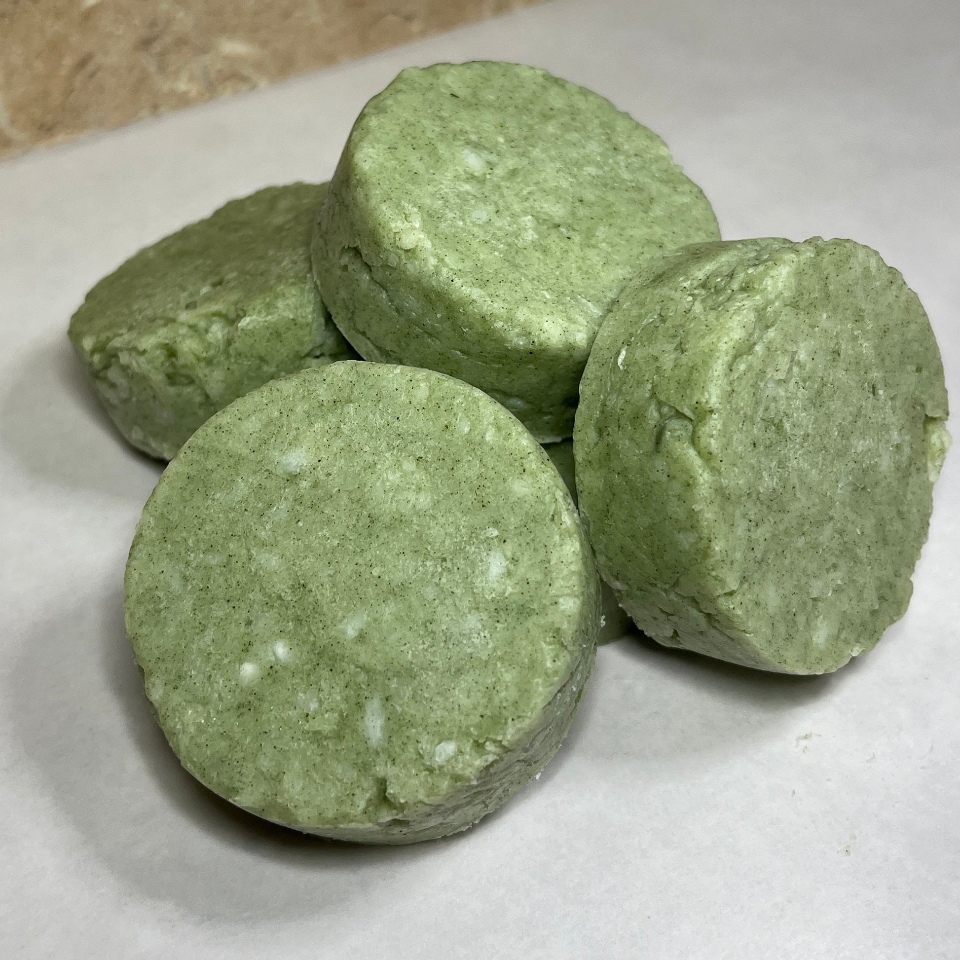 Three green syndet shampoo bars on a white surface