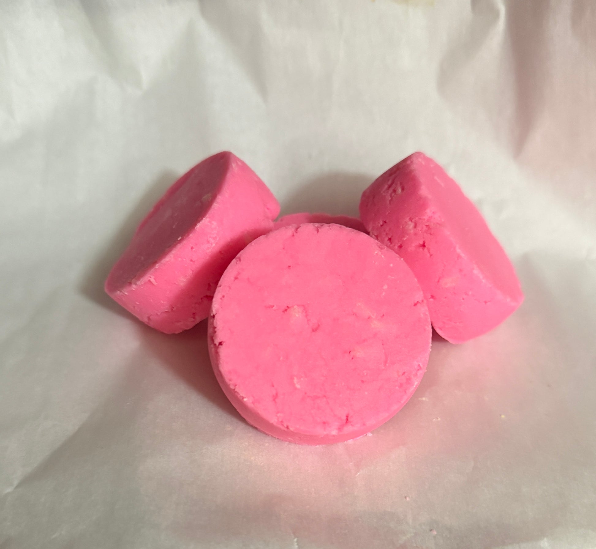 Three pink bath bombs on a white fabric background