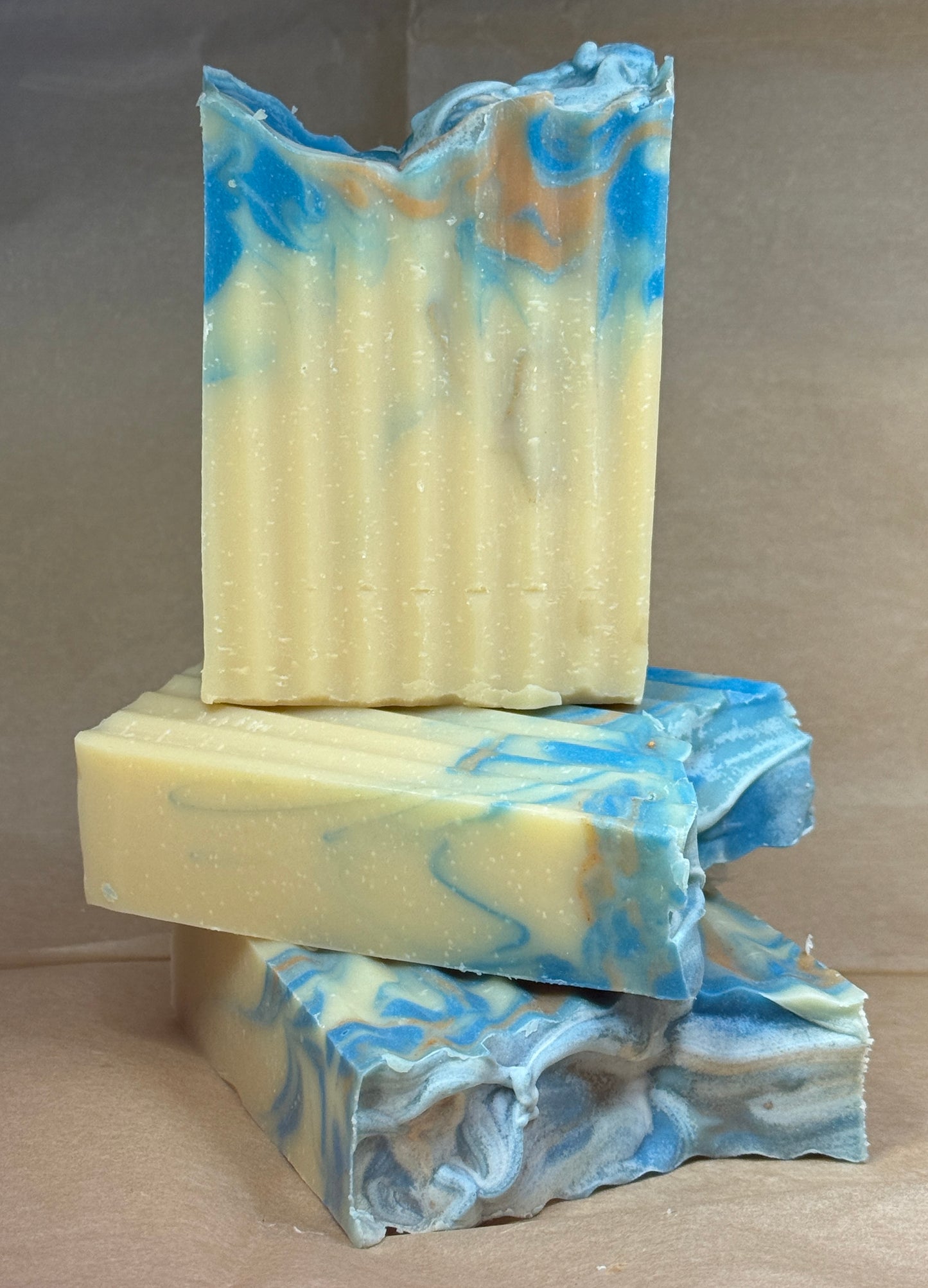 Stack of handmade soap bars with blue and white swirls on a brown background