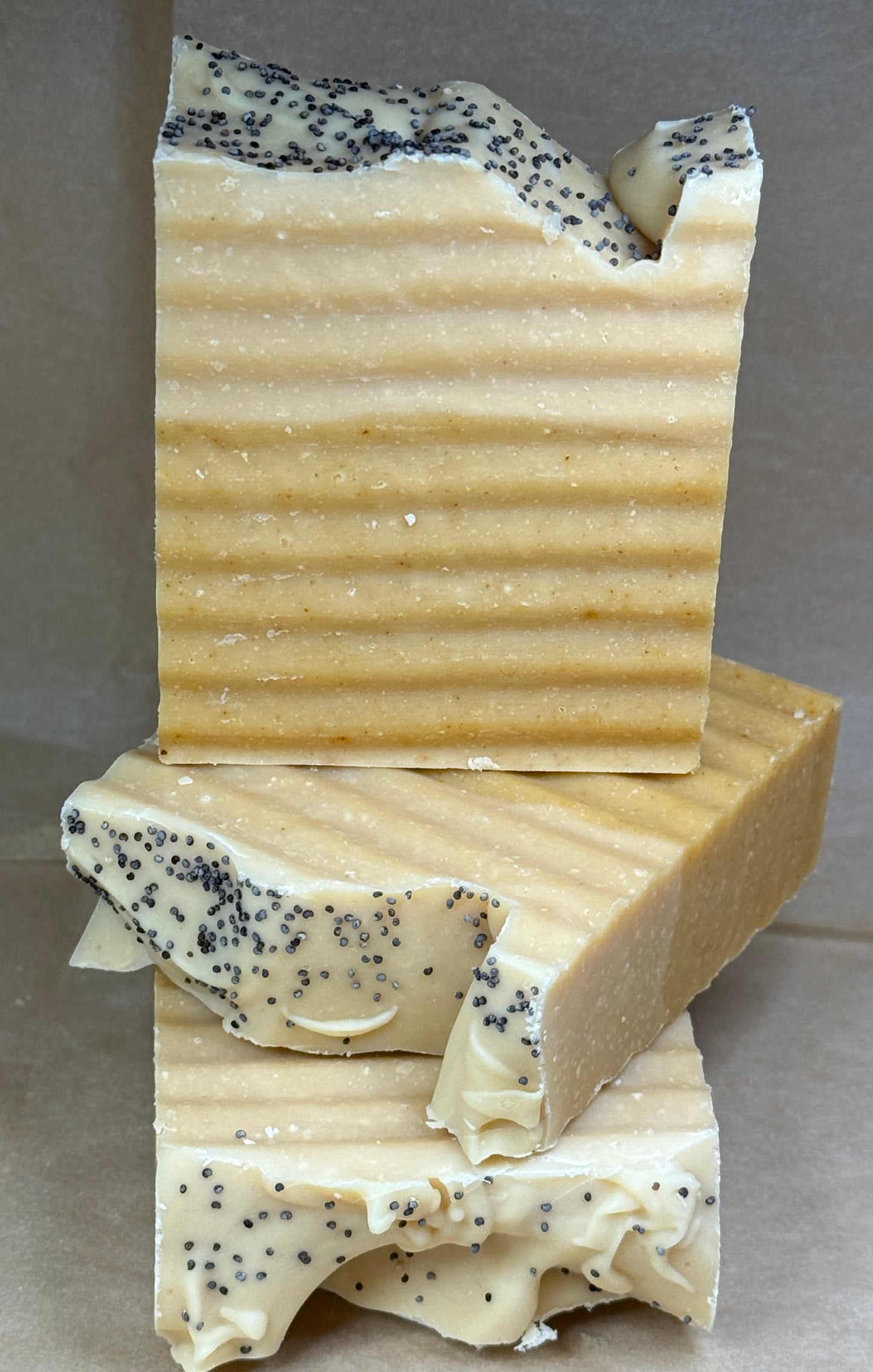 Stack of handmade soap bars with specks on a gray background